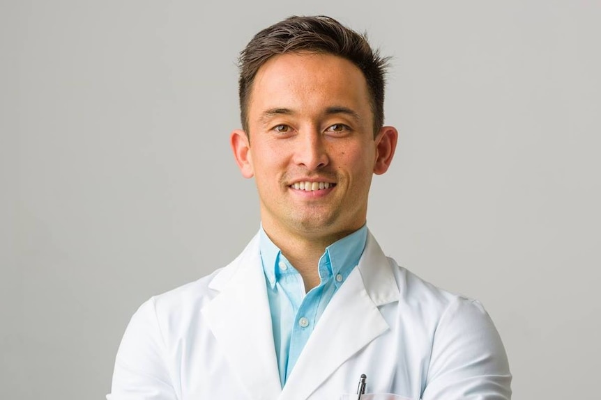 Steven Lin smiles with lab coat and blue shirt 