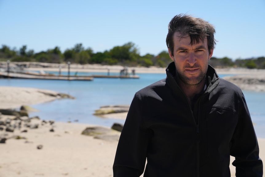 He wears a black jacket and stands by the existing channel 