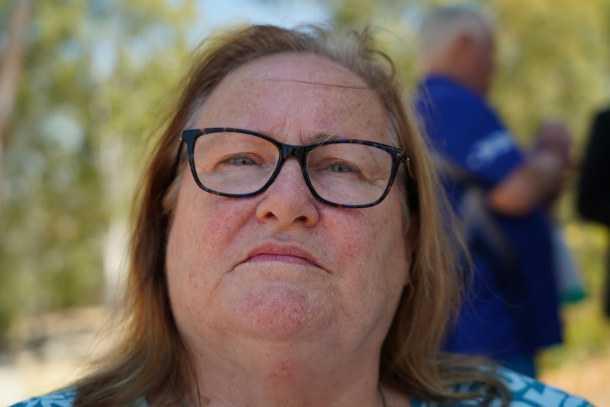 A woman with shoulder length brown/blonde hair looks at the camera.