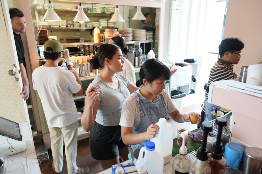 Six staff members working behind the counter at a cafe.