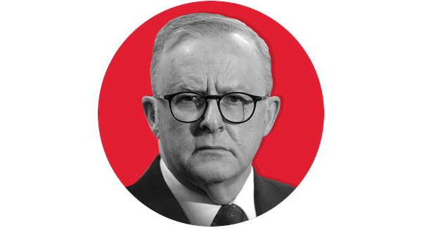 A black and white headshot of a man wearing glasses. His face sits within a red graphic circle.
