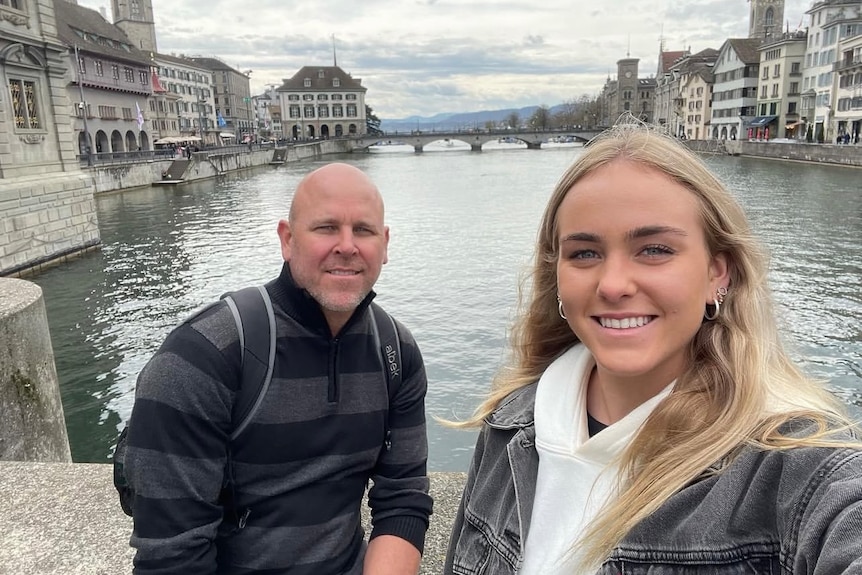 A middle aged man standing on a bridge next to a young woman.