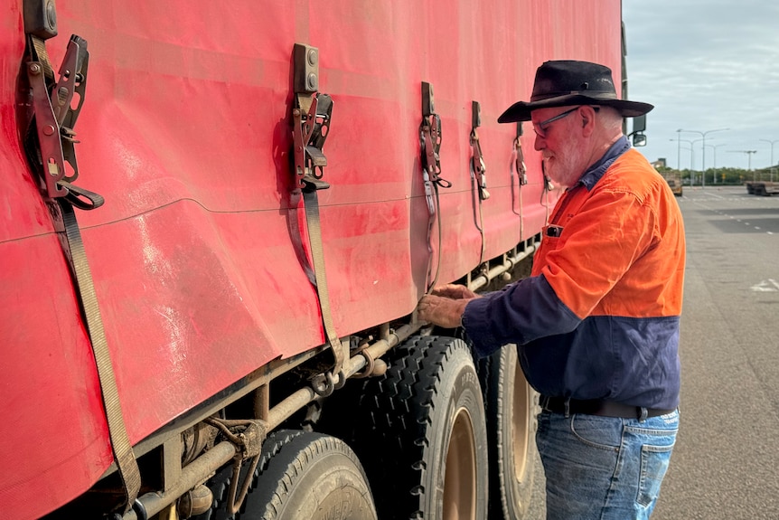 A man tying up the load on his red truck