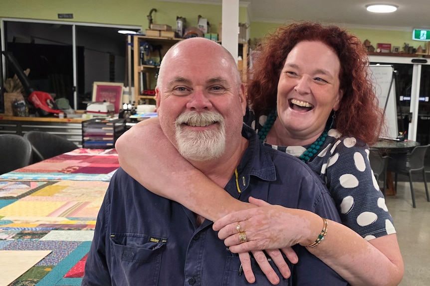 A happy couple. Lady with arms around guy and laughing.