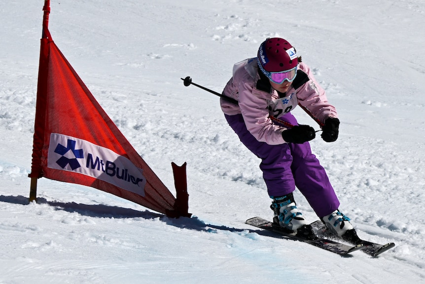 A person skiing in a race passing a flag
