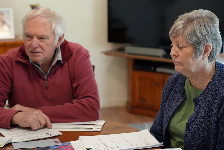 An elderly couple sit at a table.