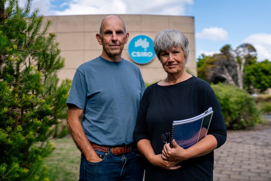 Man and woman pose for photo at a science office building by the water
