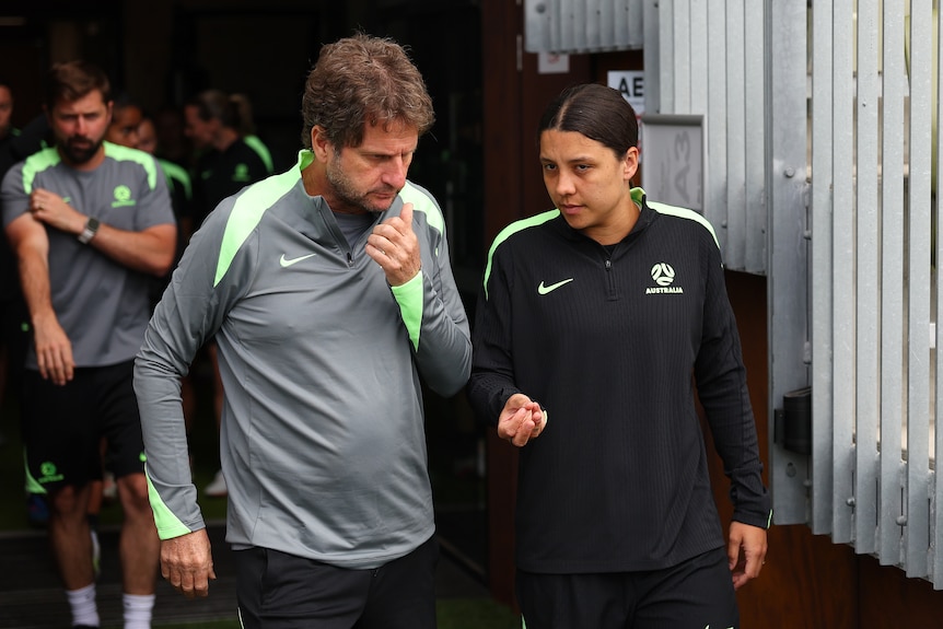 Matildas coach Joe Montemurro talks to captain Sam Kerr as they walk onto a training pitch