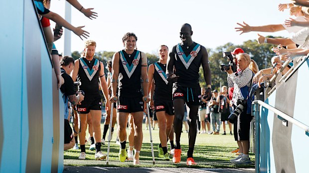 Connor Rozee leaves the field on crutches as he joins teammates in celebrating their win.