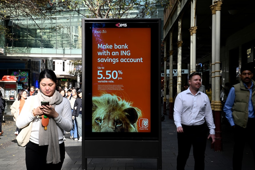 People walking through a central business district on a sunny day with a bank savings account advertisement in the centre.