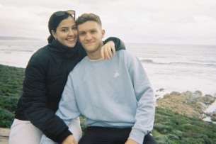 Woman with dark hair and glasses with her arm around a young man
