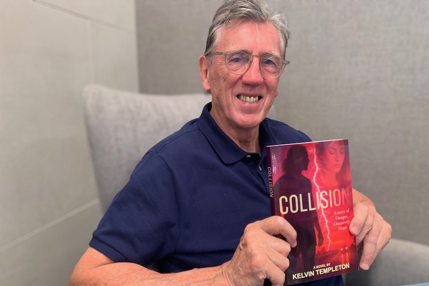 Kelvin Templeton sits smiling and holding a book.