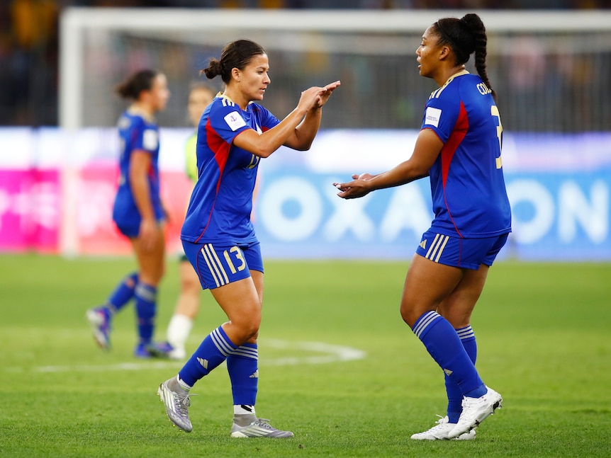 Two defenders for the Philippines slap hands in connection during a game against Australia.
