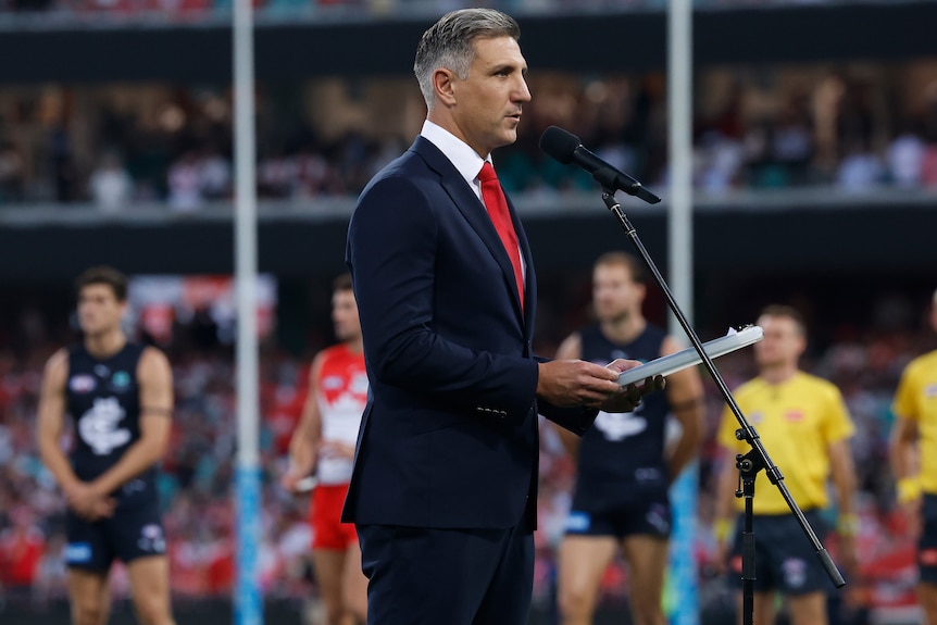 Matthew Pavlich speaking behind a microphone ahead of the 2026 Swans vs Blues AFL match at the SCg.