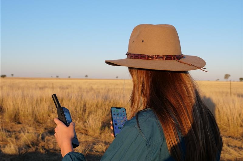 woman holds phone in rural area