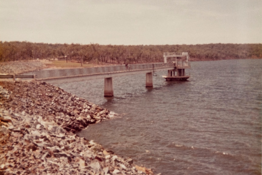 A jetty over the water with rocks in the foreground