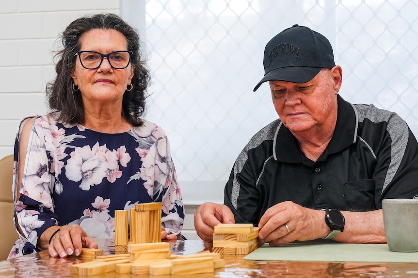 A man and a woman doing a Jenga at a table.