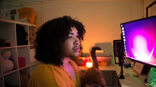 Ezra Burke, pictured with their cat Patrice, bought a ChatGPT subscription when their NDIS support for psychotherapy was cut, and feels conflicted about using it. 