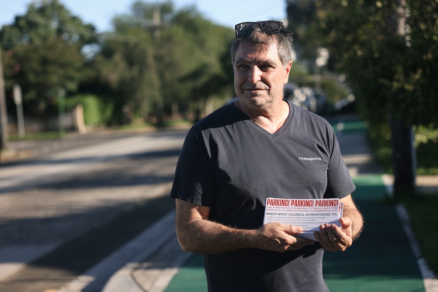 a man standing on a cycleway holding small flyers in his hands
