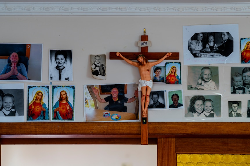 A wall with a crucifix surrounded by family snapshots