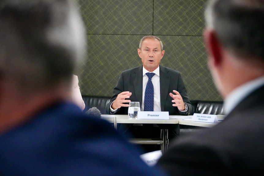 A man moves his hands as he speaks at a meeting