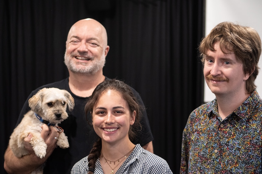 Older man, young woman and young man look at camera, all smiling