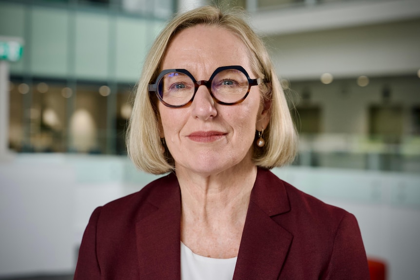 A white woman with short blonde hair and glasses 