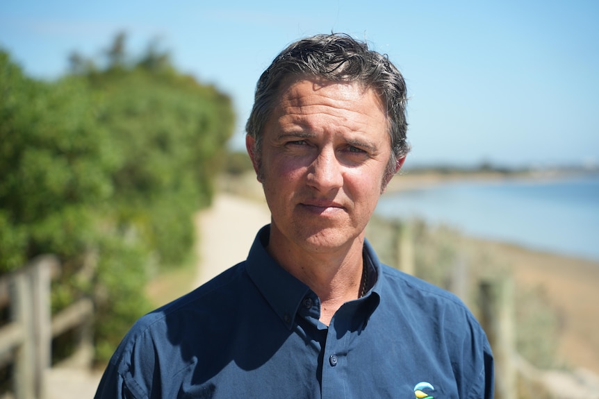 Gareth Smith smiles at the camera with the sea in the background.