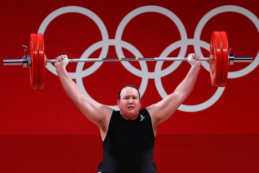 Weightlifter Laurel Hubbard holds a weights above her head dressed in a black singlet
