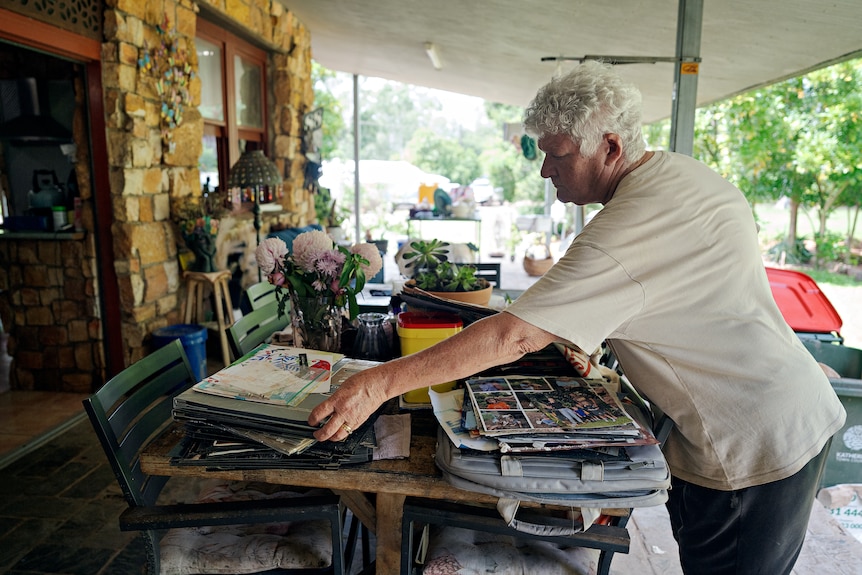 A woman sorts through a pile of photo albums.
