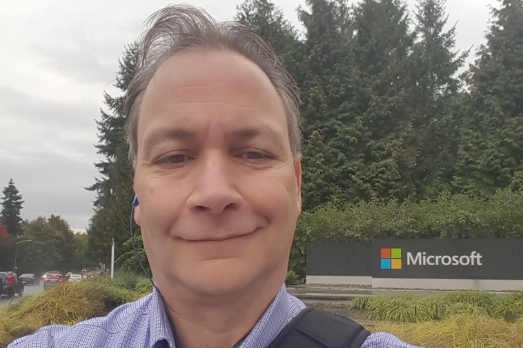 A man stands in front of a Microsoft sign.