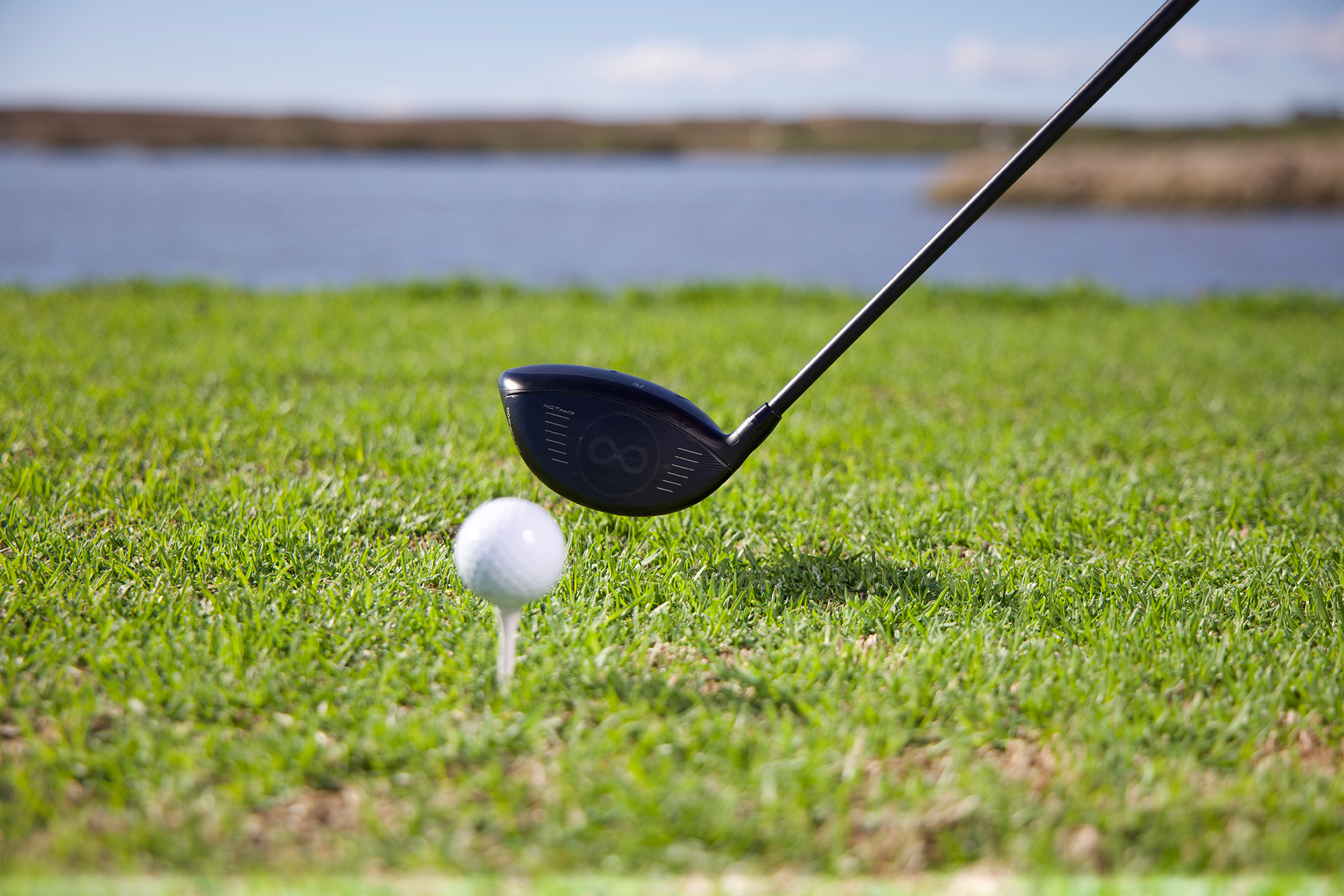 The driver head behind the golf ball moving into impact, with the golf ball on a tee