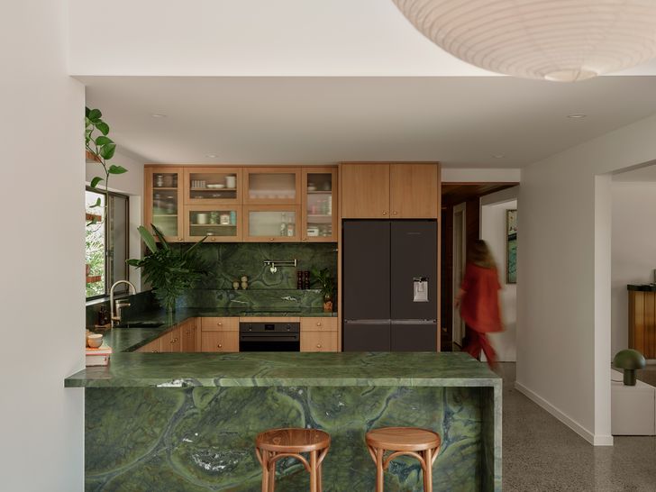 The kitchen feels tactile and warm, with a Quartzite bench and splashback in a green, leather-look finish.