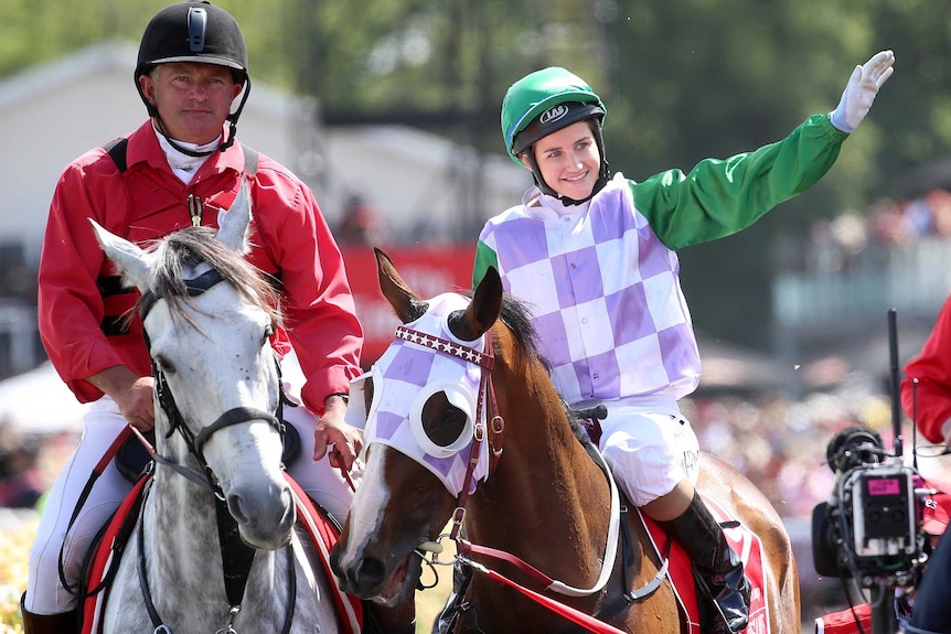 Michelle Payne waves to the crowd from atop a horse, Prince Of Penzance, after winning the Melbourne Cup.