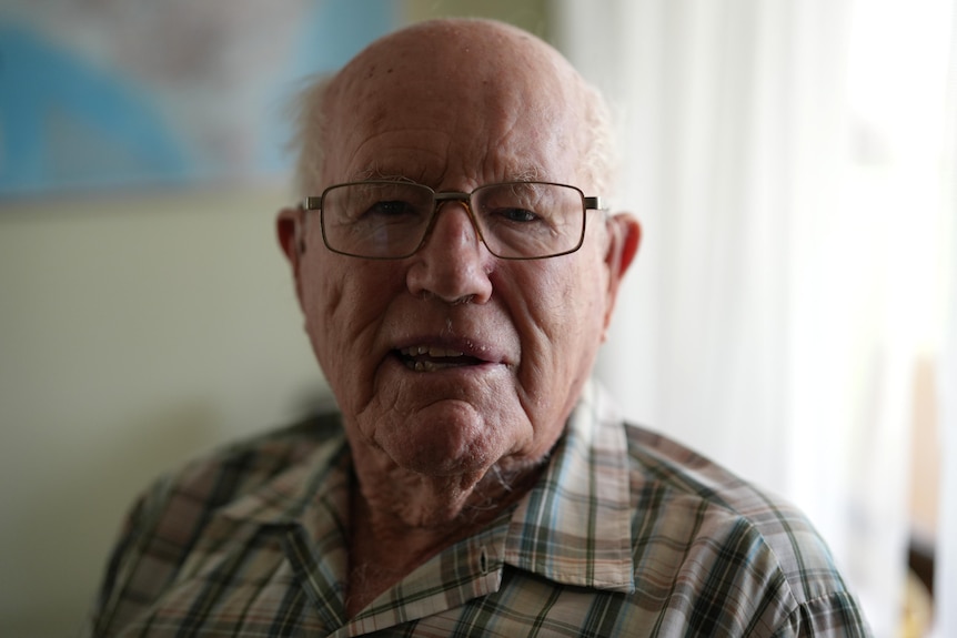 Robert Tucker looks toward camera, wearing checked shirt