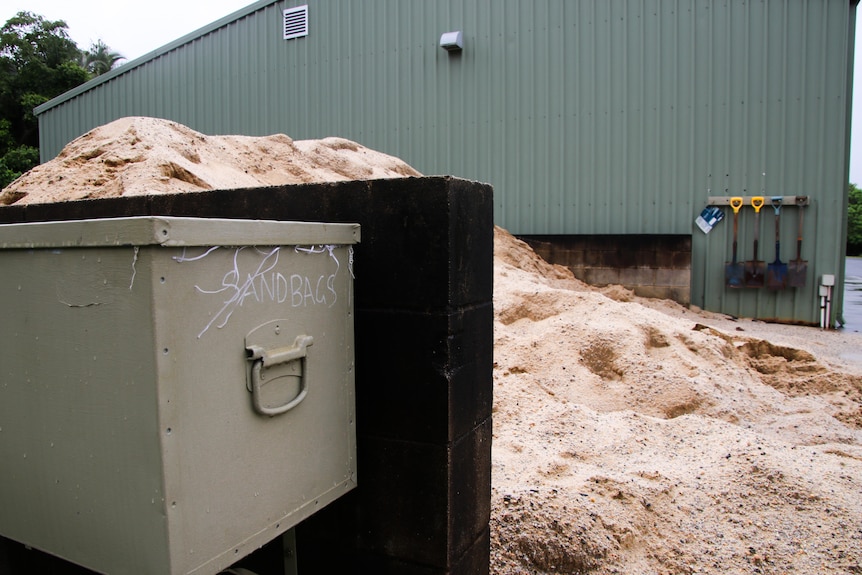 A pile of sand for sandbagging sits outside an industrial building.