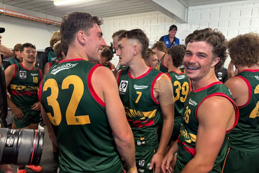 a group of men stand around in green football jerseys