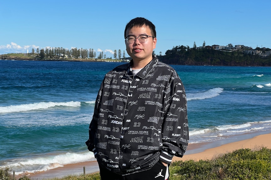 A young man standing by a beach.