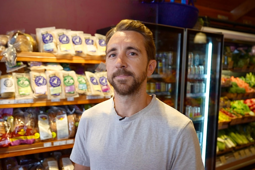 A man in a grocery store smiles at the camera.