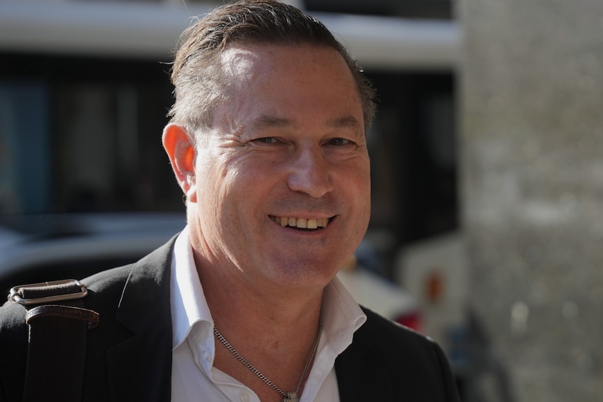 Man smiling in dark jaccket and white shirt