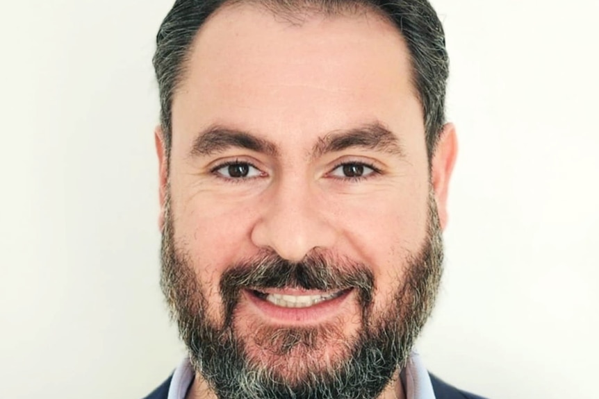 A smiling man with a moustache and beard.