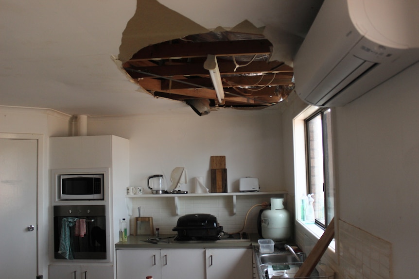 The kitchen roof of a house is damaged and peeled off by a cyclone, with timber frame surfaced. 