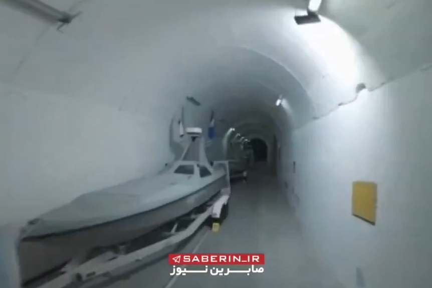 A close up of a silver spped boat housed in an underground cement facility.