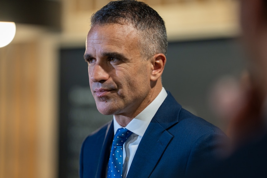 A man with a serious expression wearing a navy suit and tie