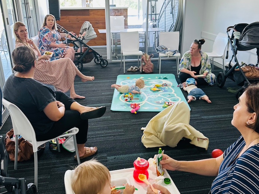 A group of woman talking in a room with babies around them