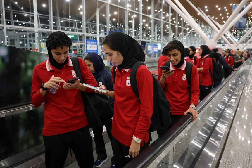 Members of the Iranian women's national soccer team on an escalator at Kuala Lumpur International Airport