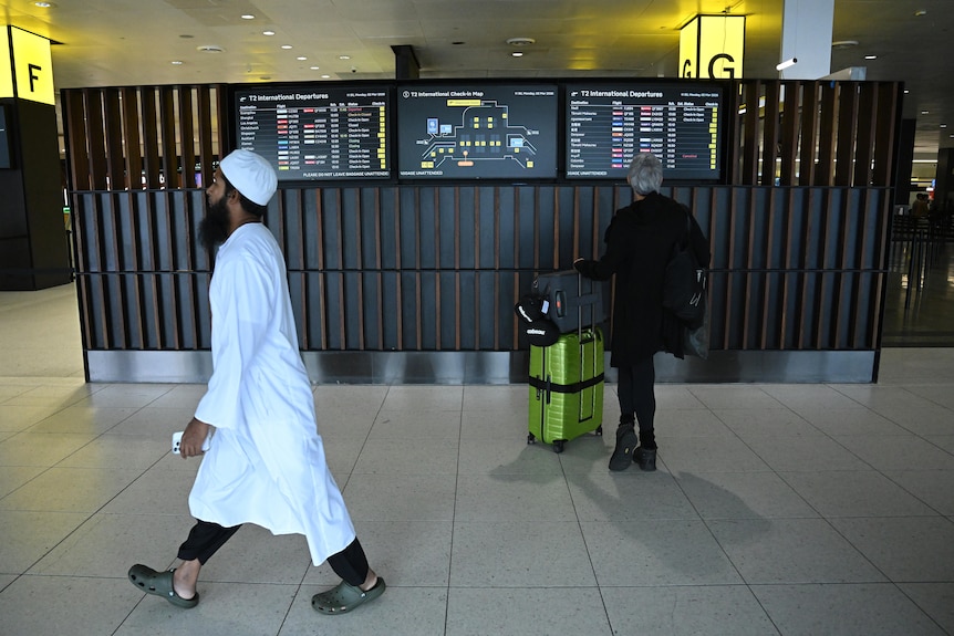 A person is seen looking a screen displaying international departures at Melbourne International Airport