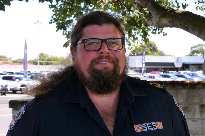 A man with a round face and galsses weating a SES uniform.