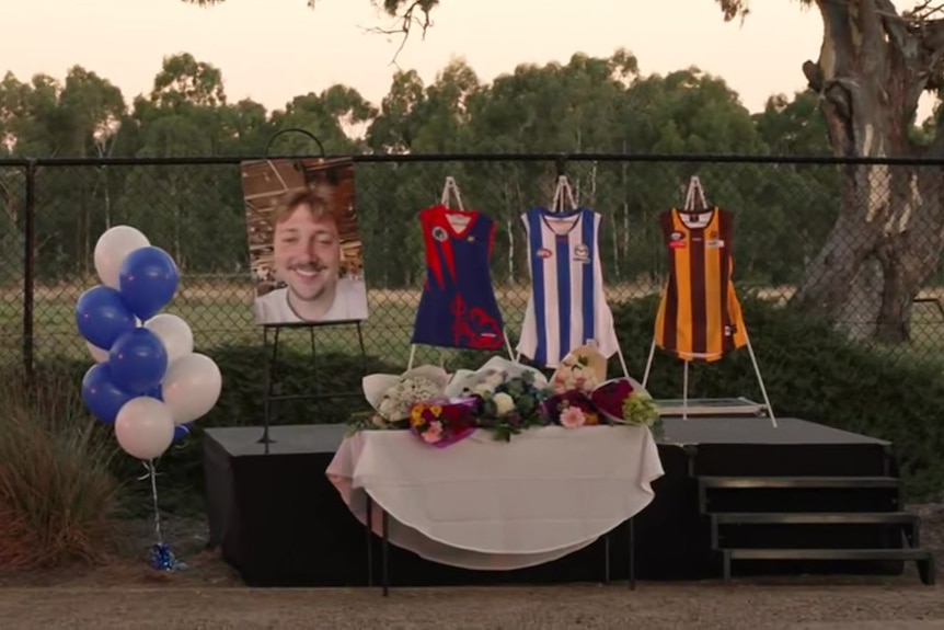 A large photo of Aidan Becker, along with footy jumper and balloons at the vigil
