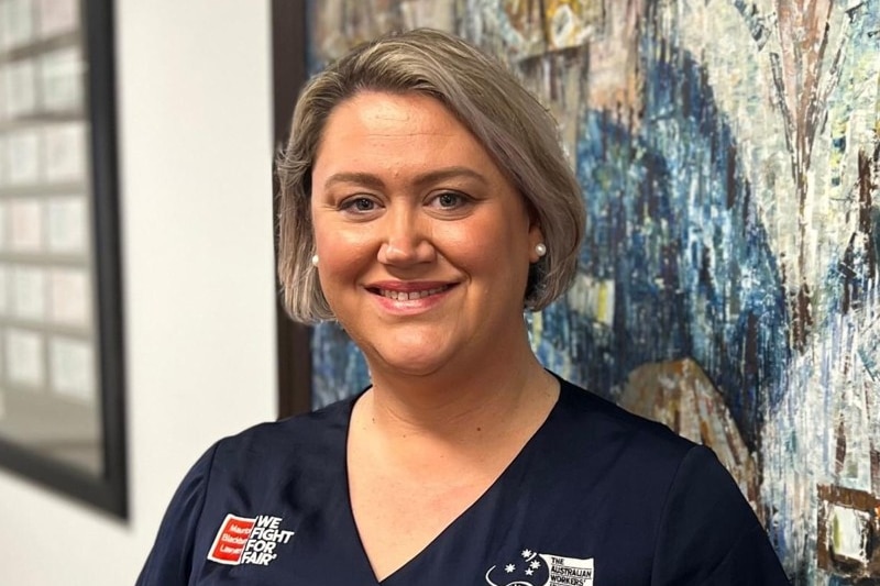 A smiling blonde woman in a dark shirst with an Australian Workers Union logo.  